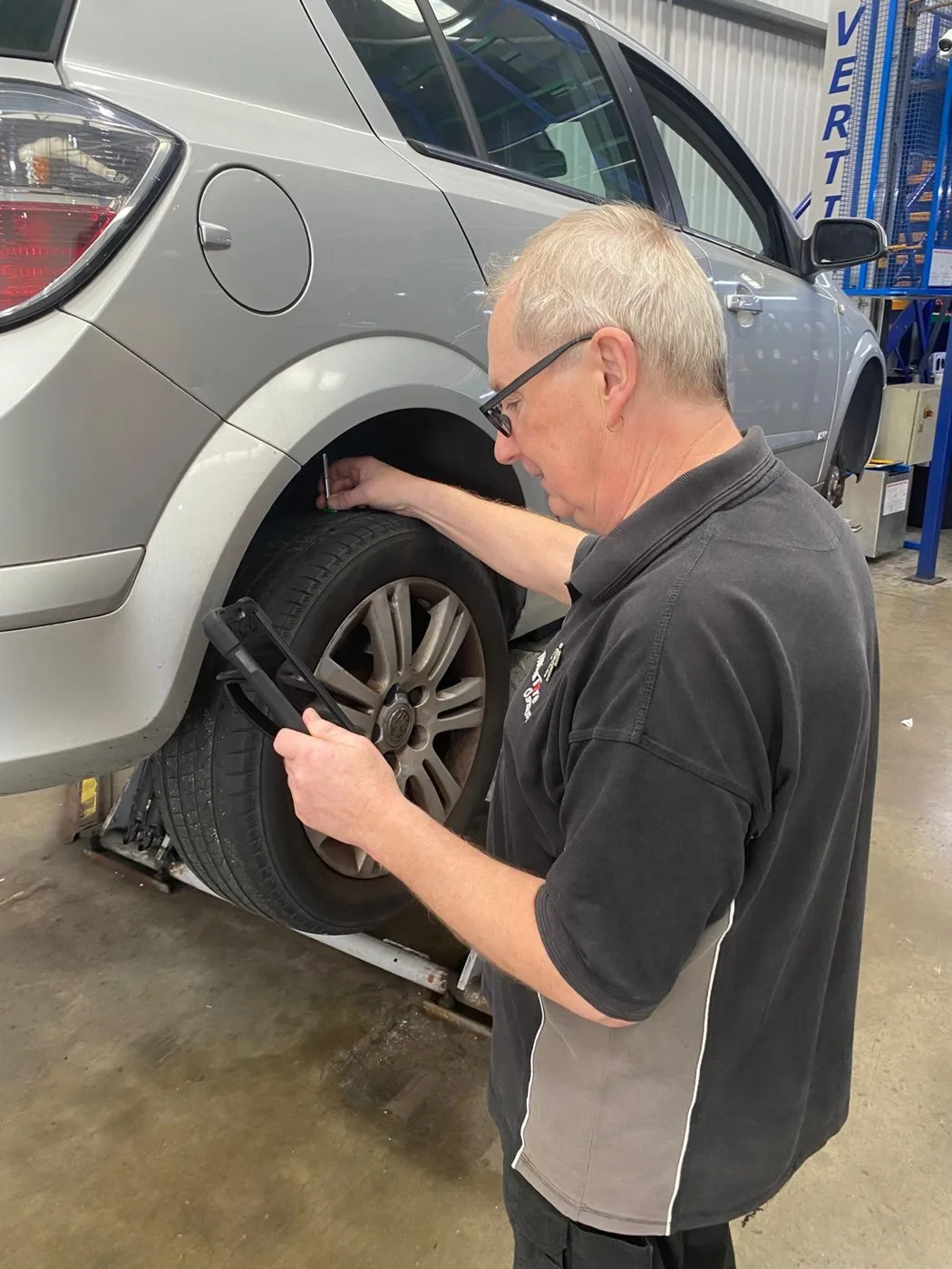 A Merityre technician measures the tread depth on a car's rear tyre